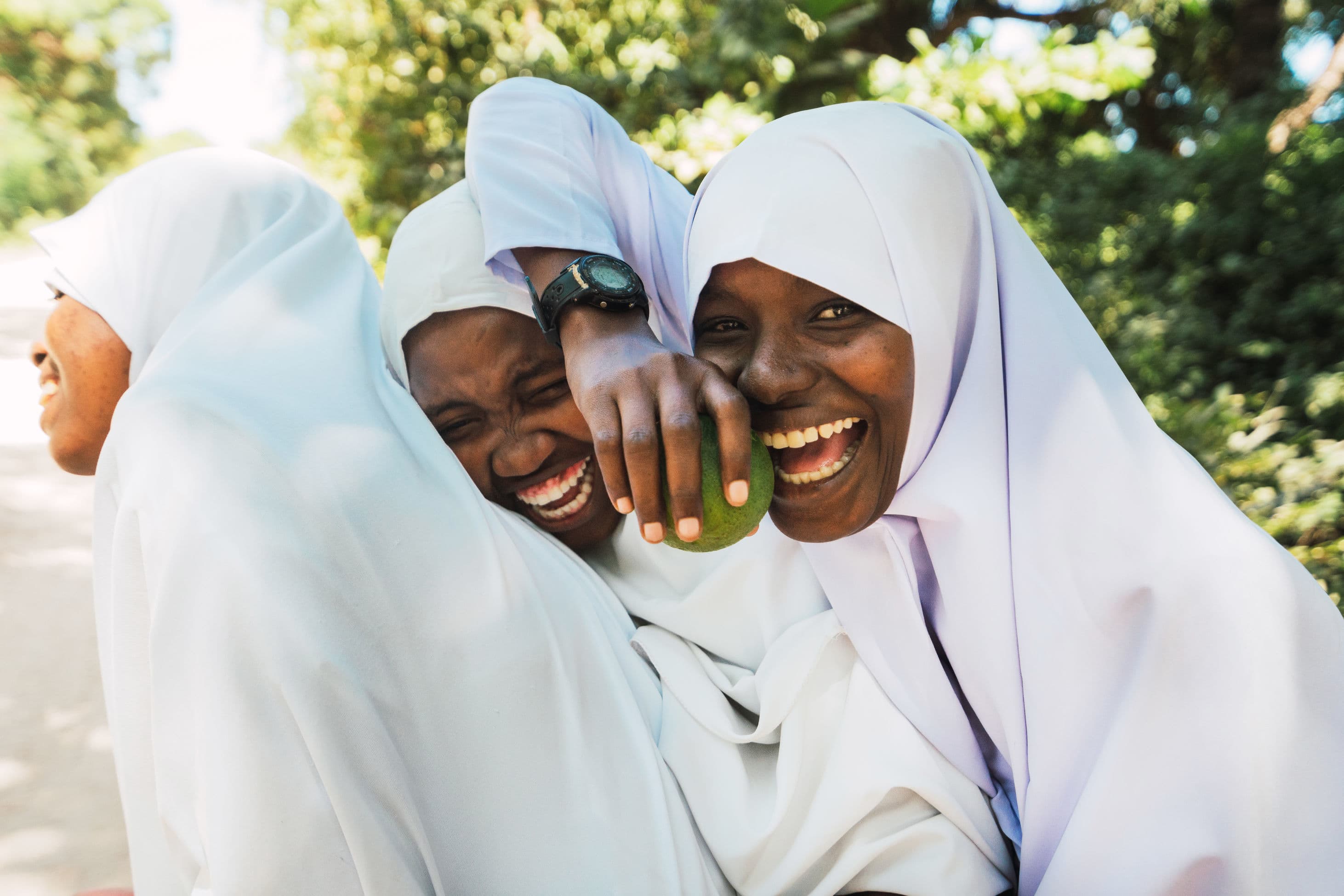 3 young women laughing with apple