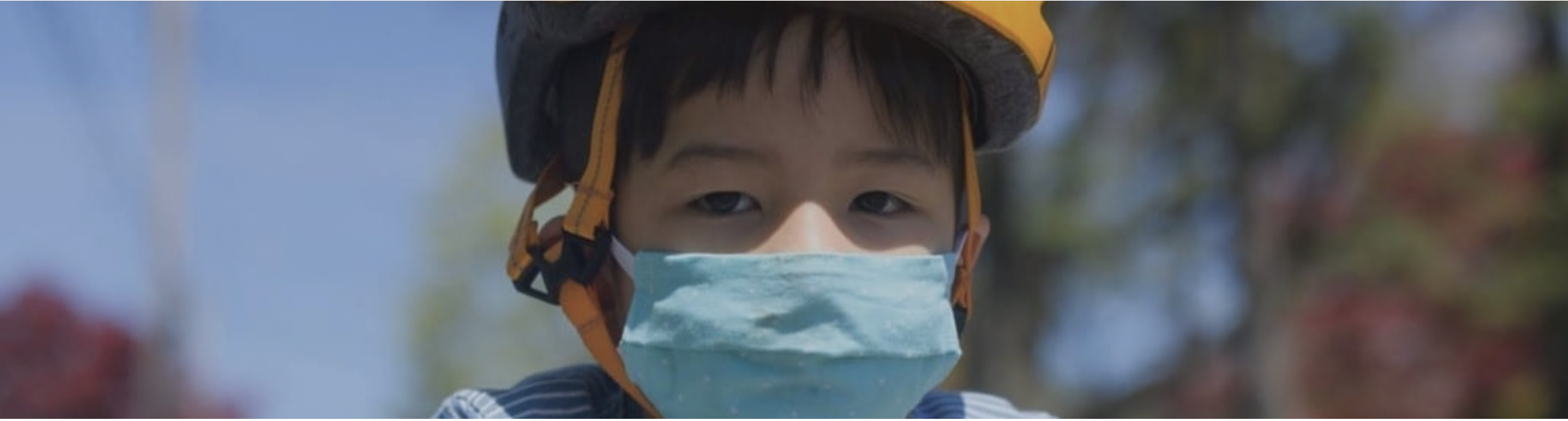 Child riding a bike wearing mask