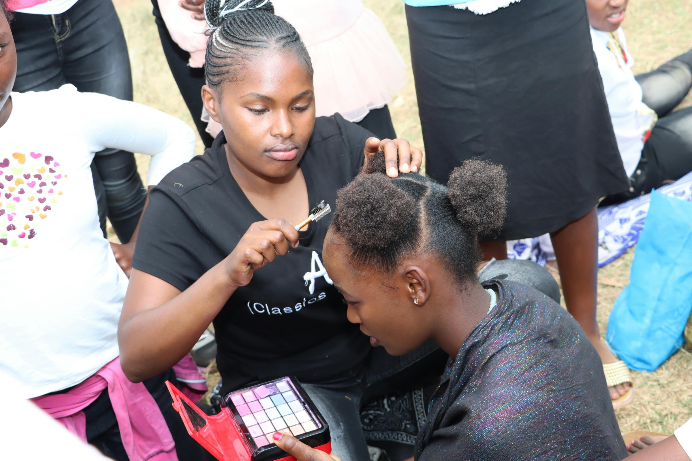 DREAMS girl using her make up skills to prep one of the girls during an "End GBV" advocacy event.