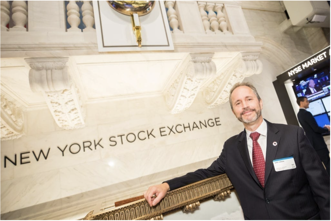 Gary Cohen stands by the bell of the New York Stock Exchange.